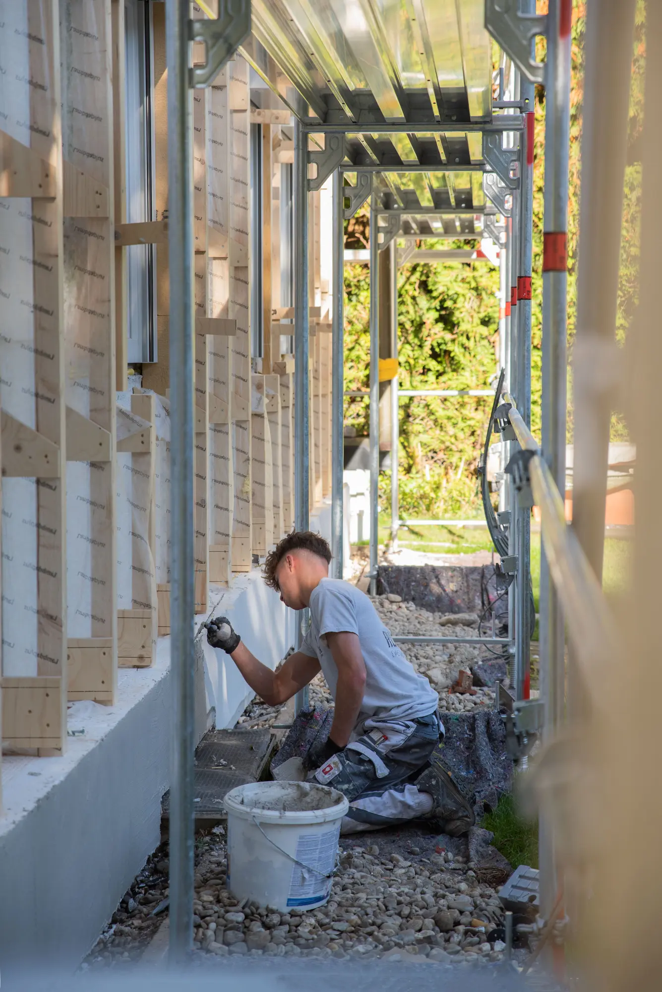 Handwerker verputzt einen Fassadensockel im Gerüst