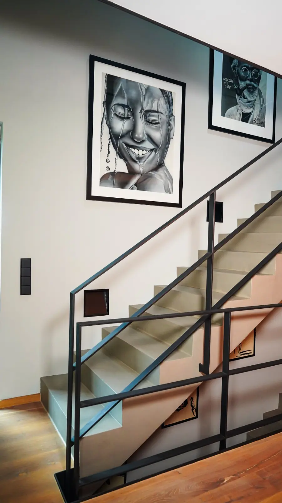 Individueller Innenausbau in München mit maßgefertigter Betontreppe, schwarzem Stahlgeländer und Kunstwerken